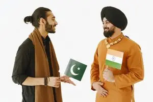 India Pakistan nuclear war: Two men, holding Indian and Pakistani flags, engage in friendly conversation.