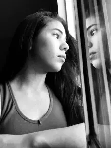 Young Girl and Death: woman in tank top looking out the window